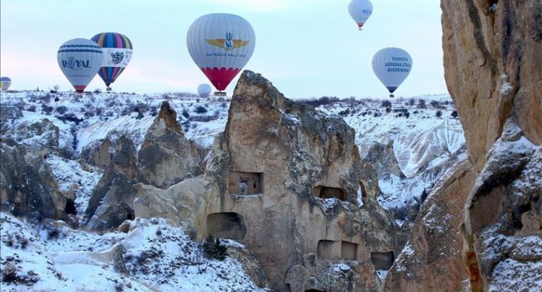 Туристы наслаждаются видами заснеженной Каппадокии с высоты птичьего полета